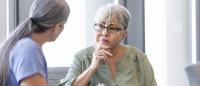 older woman in doctors office talking to her doctor about colonoscopy